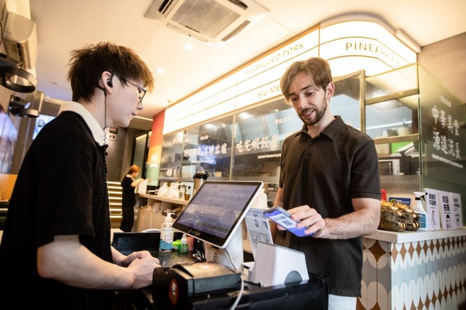 Un viajero internacional paga en un restaurant con Alipay.